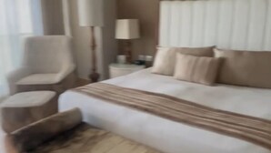 A hotel room with a large bed, a chair, a nightstand, and a bench. - Grand Luxxe at Vidanta Nuevo Vallarta (Nuevo Nayarit)