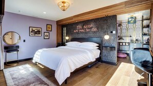 Ein modernes Schlafzimmer mit einem großen Bett, einem Schminktisch mit Spiegel und einer Wand mit einer dekorativen Schrift.