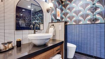 Une salle de bain moderne avec un grand lavabo, un miroir et un espace douche.