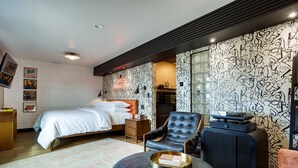 A modern bedroom with a bed, a leather armchair, a coffee table with a book, and a unique wall design. - The Reed @ The Louie Boutique Motel, Private Sauna! Walk to Everything! (Newport)