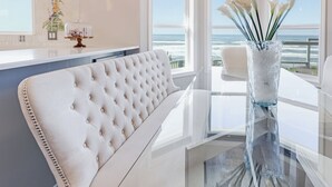 A modern kitchen with a white bar and a view of the ocean.