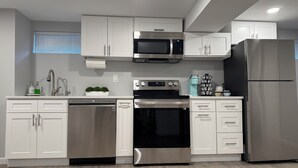 A modern kitchen with white cabinetry, stainless steel appliances, and a wooden floor. - Boutique Studio 10 min. walk to UBS Arena (Elmont)