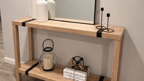 A wooden console table with a mirror, shelves, and decorative items. - Boutique Studio 10 min. walk to UBS Arena (Elmont)