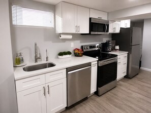 A modern kitchen with white cabinetry, stainless steel appliances, and a wooden floor. - Boutique Studio 10 min. walk to UBS Arena (Elmont)