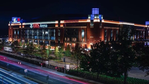 A modern building with a prominent UBS Arena sign, surrounded by trees and a busy street with light trails. - Boutique Studio 10 min. walk to UBS Arena (Elmont)