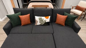 A sectional sofa with a central backrest and two side sections, featuring a variety of pillow designs. - Boutique Studio 10 min. walk to UBS Arena (Elmont)