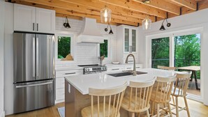 Una cocina moderna con refrigerador de acero inoxidable, armarios blancos y una isla grande con taburetes de madera.