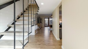 Eine moderne Treppe mit Metallgeländer, Holzboden und einer weißen Ziegelwand.