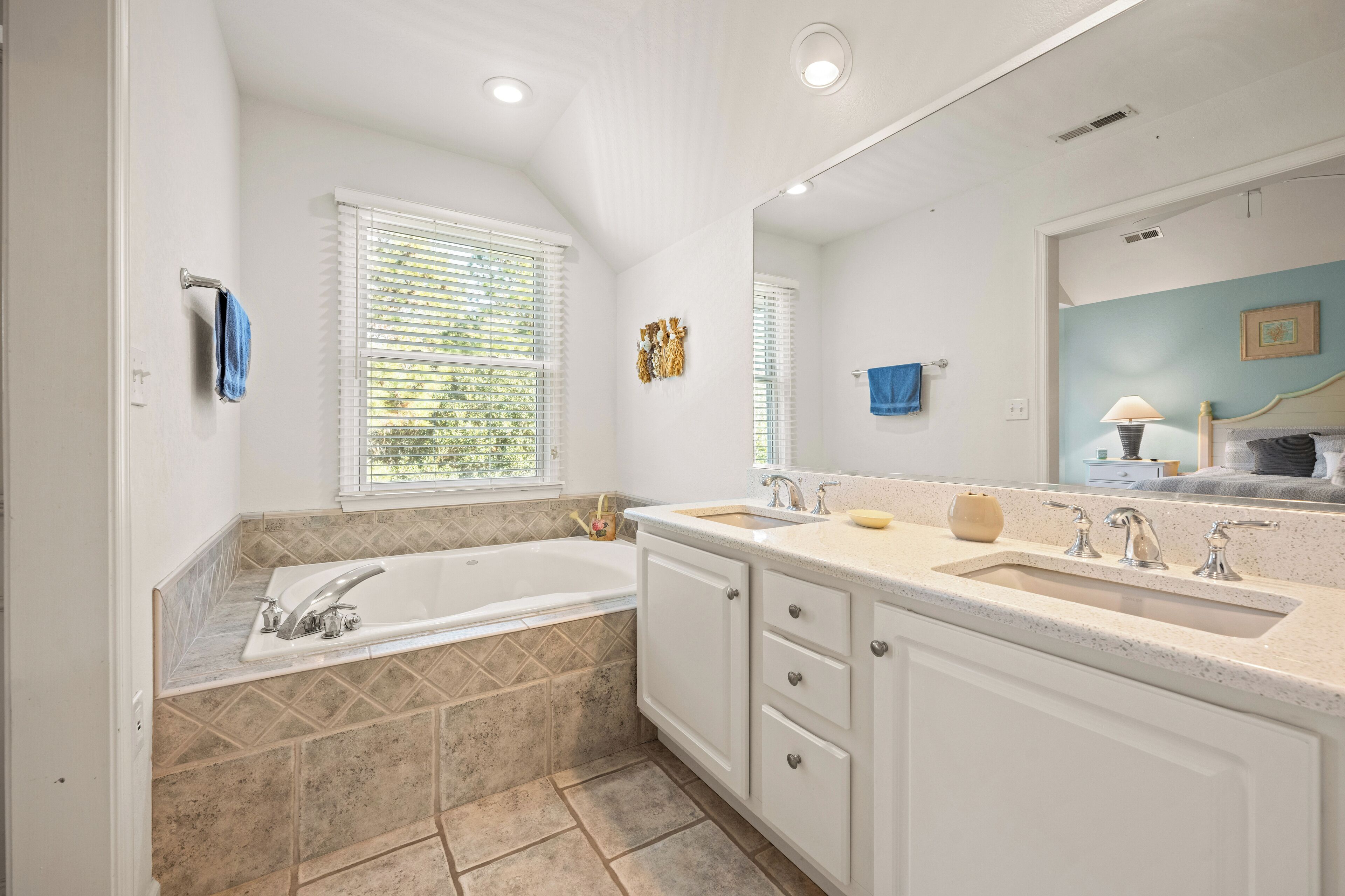 A modern bathroom with a large bathtub, two sinks, and a vanity with drawers.