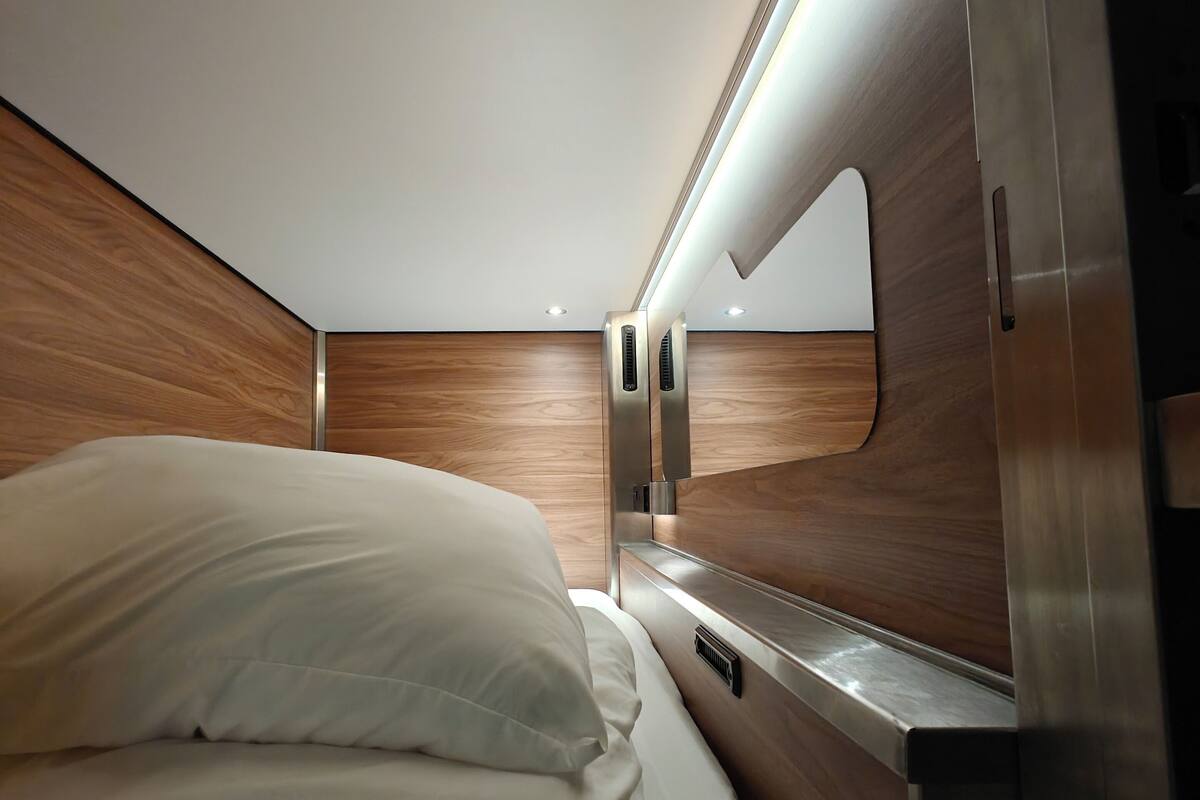 A modern interior with a bed, wooden paneling, and a built-in mirror.