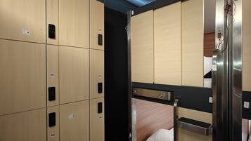 A hotel room with bunk beds, a wardrobe with numbered compartments, and a small desk area.