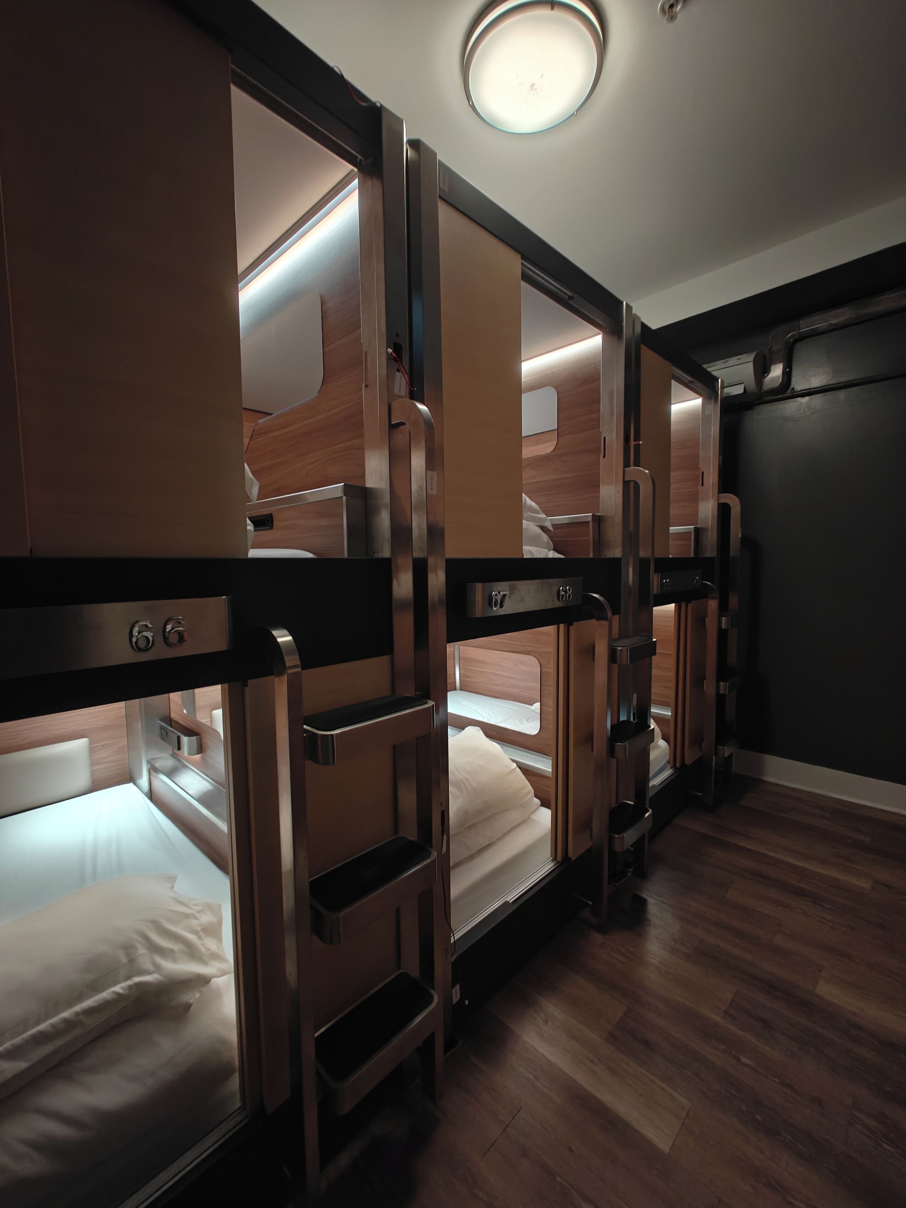 A train car with bunk beds, wooden paneling, and a small kitchenette.