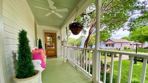 A porch with a white railing, a ceiling fan, and a potted plant. - 1883 Boutique Bungalow (McKinney)