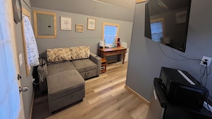 Un salon moderne comprenant un canapé, une table basse, un téléviseur et un bureau avec un ordinateur.