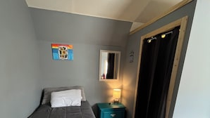 Une chambre à coucher avec un lit, une table de chevet, un miroir et une porte.