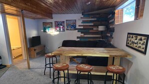 Une pièce chaleureuse avec une table en bois et des tabourets de bar, un canapé et un mur décoré d’œuvres d’art sur le thème de la Route 66.