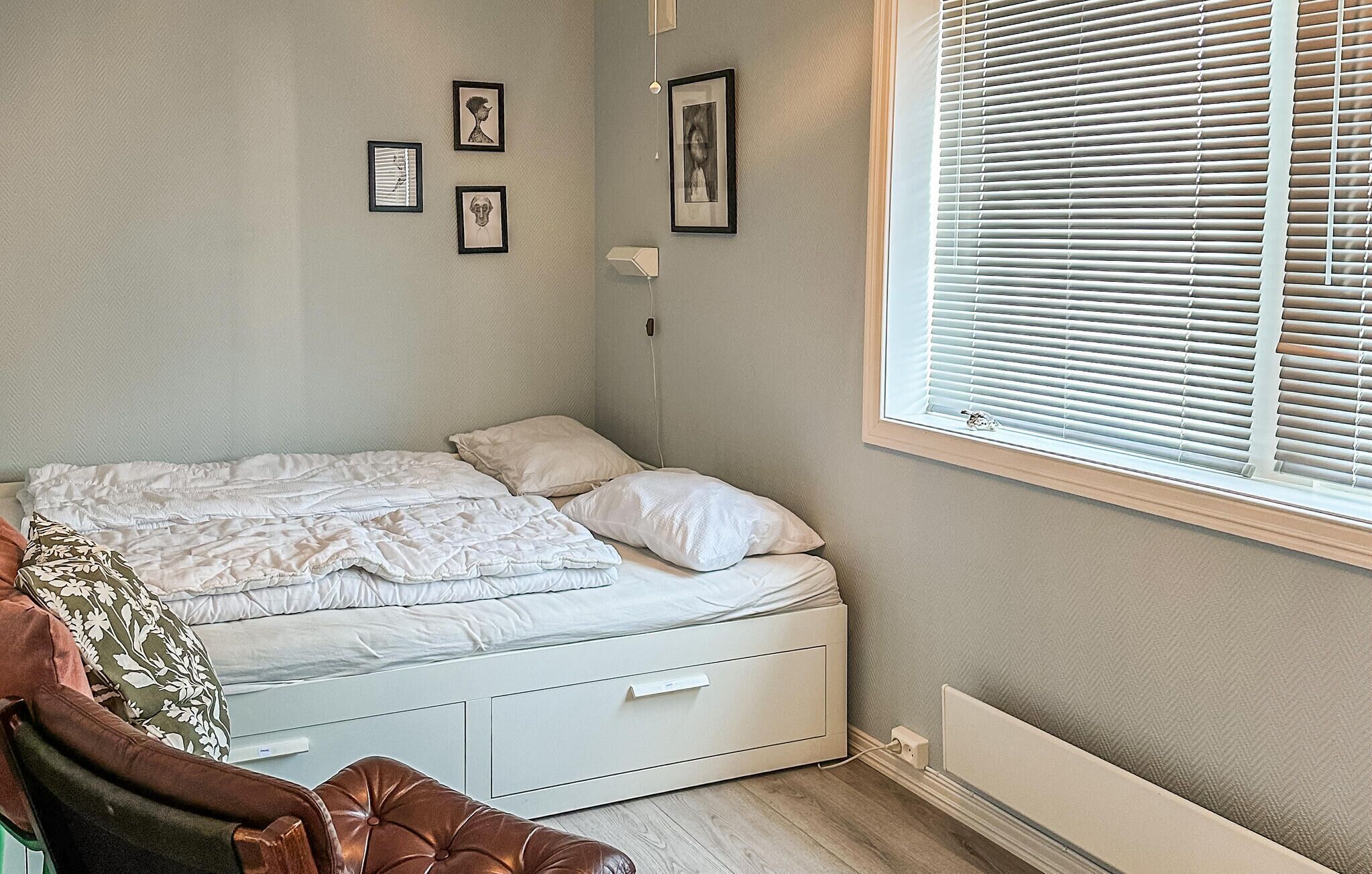 Une chambre à coucher avec un lit, une table de chevet, une lampe et une fenêtre avec des stores.