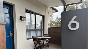 A modern exterior with a blue door, a wooden table and chairs, a large window, and a number '6' sign.