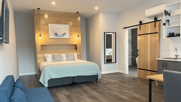 A modern bedroom with a bed, bedside table, and a wardrobe.