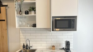 A modern kitchen with grey cabinets, a built-in microwave, a sink, and a coffee machine.