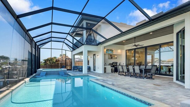 Ein moderner, überdachter Pool mit Glaswänden, eine Terrassenfläche mit Sitzgelegenheiten und Blick auf die umliegende Landschaft.