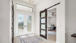 Ein Flur mit Doppeltüren, einem gemusterten Teppich und einem Deckenventilator.