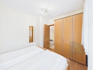 A bedroom with a bed, a wardrobe, and a mirror.