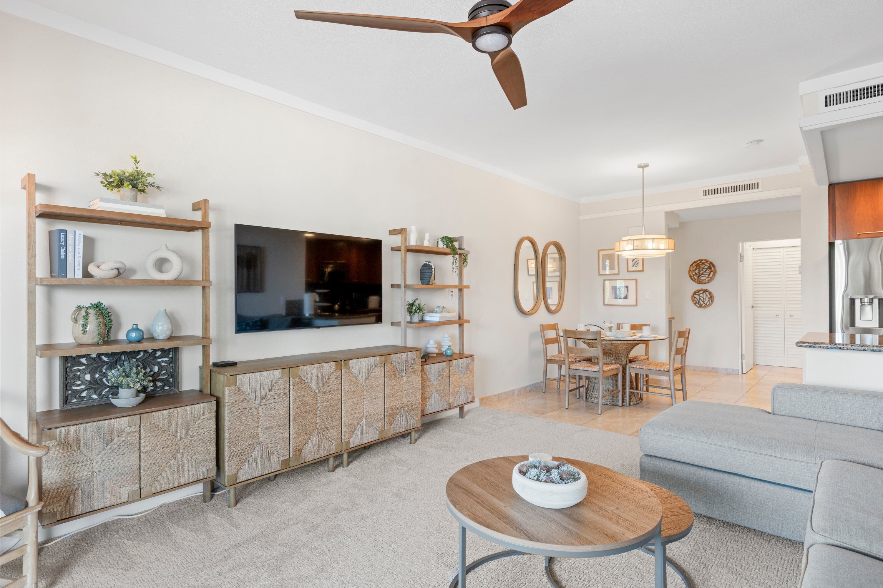 Un salon moderne avec un téléviseur, des meubles en bois et un ventilateur de plafond.