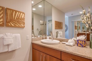 Bathroom features a large mirror, round sink, and wooden cabinets.