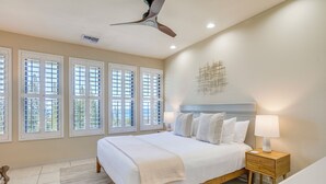 Une chambre à coucher avec un grand lit, un ventilateur de plafond et une table de chevet avec une lampe.