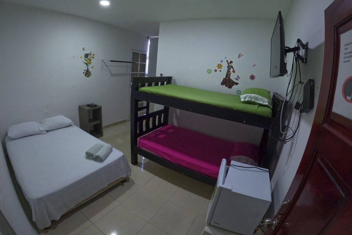 A dormitory room with a bunk bed, a desk, a chair, and a small cabinet.
