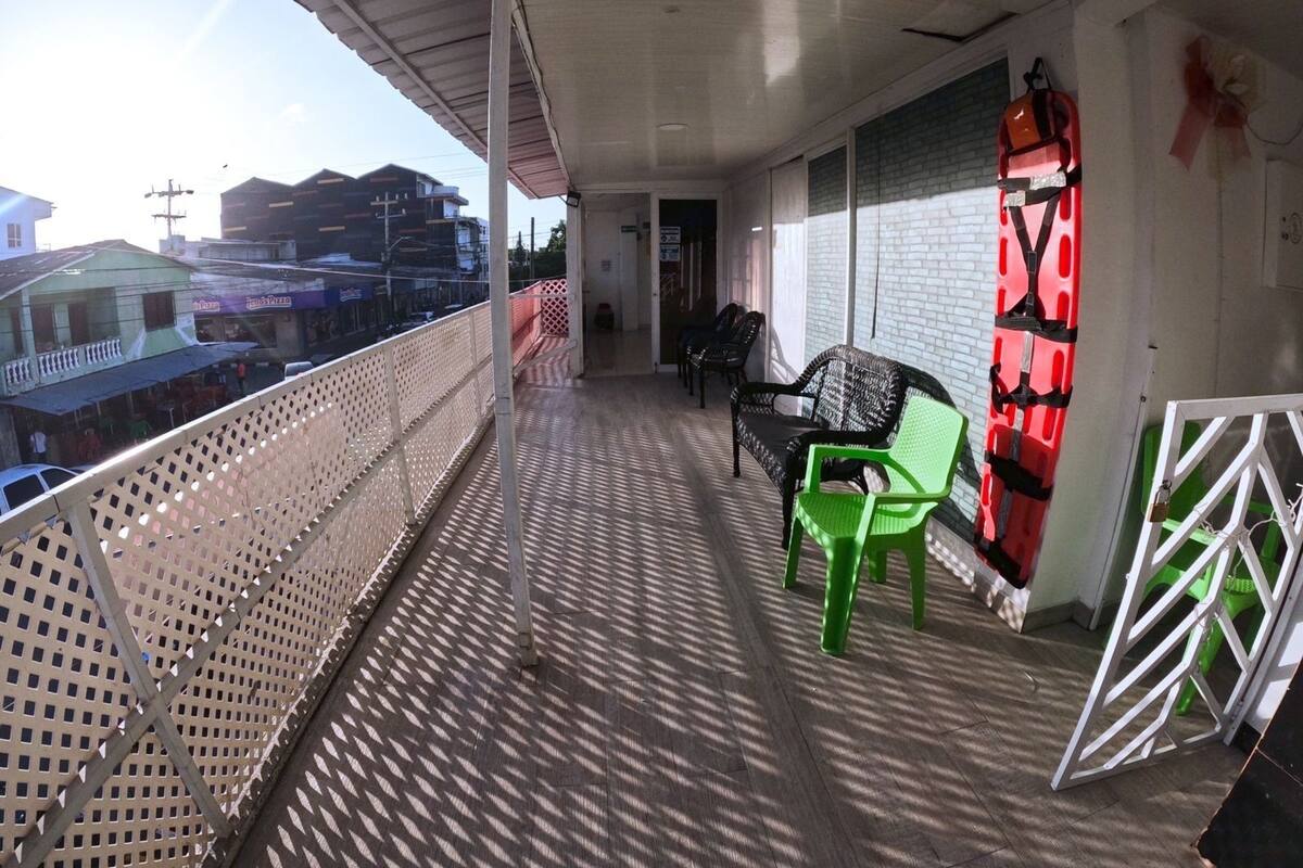 A balcony with a metal railing, a green chair, and a red chair.