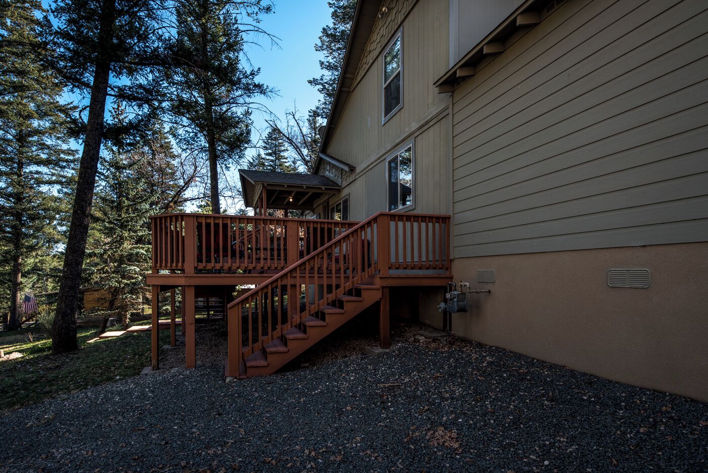 A two-story house with a wooden deck and stairs leading to a covered porch.