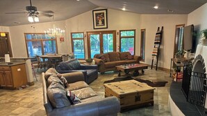 A spacious living room with leather sofas, a wooden coffee table, and a fireplace. - Riverside Retreat (Ruidoso)