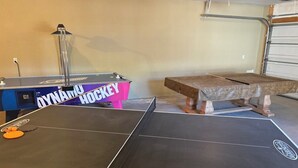 A ping pong table in a room with a blue cabinet and a pink table with 'DYNAMIX HOCKEY' written on it. - Riverside Retreat (Ruidoso)