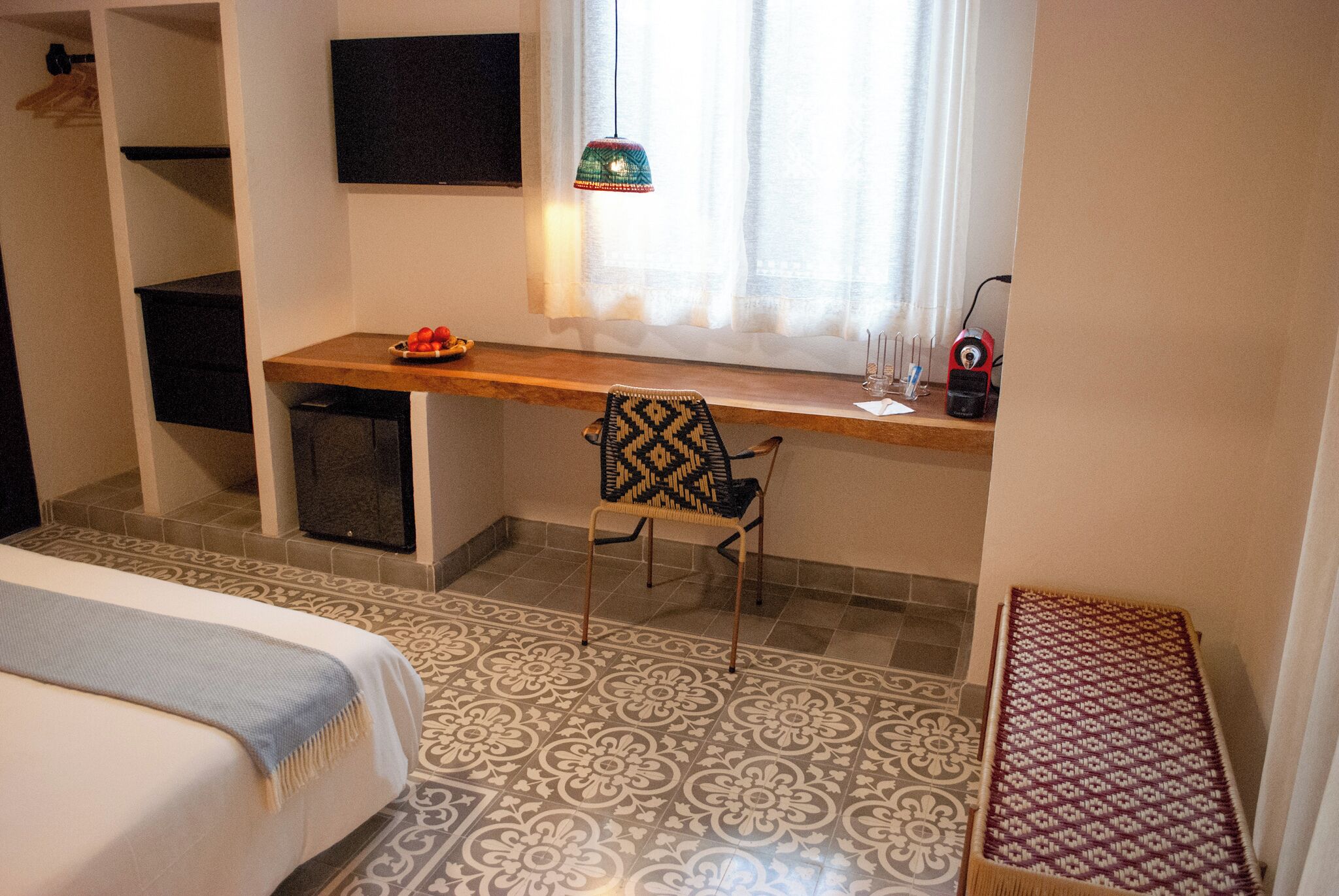 Un dormitorio con cama, escritorio con silla, una mesita y ventana con cortinas.