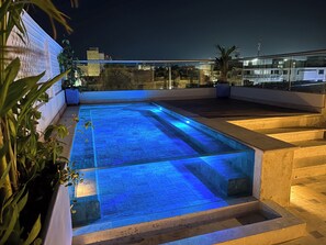 A rooftop pool with blue lighting, surrounded by plants and a cityscape view. - Hotel Casa de la Acequia (Santa Marta)