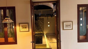 An open doorway leading to a hallway with a stone wall, a wooden door frame, and a hanging light fixture. - Hotel Casa de la Acequia (Santa Marta)
