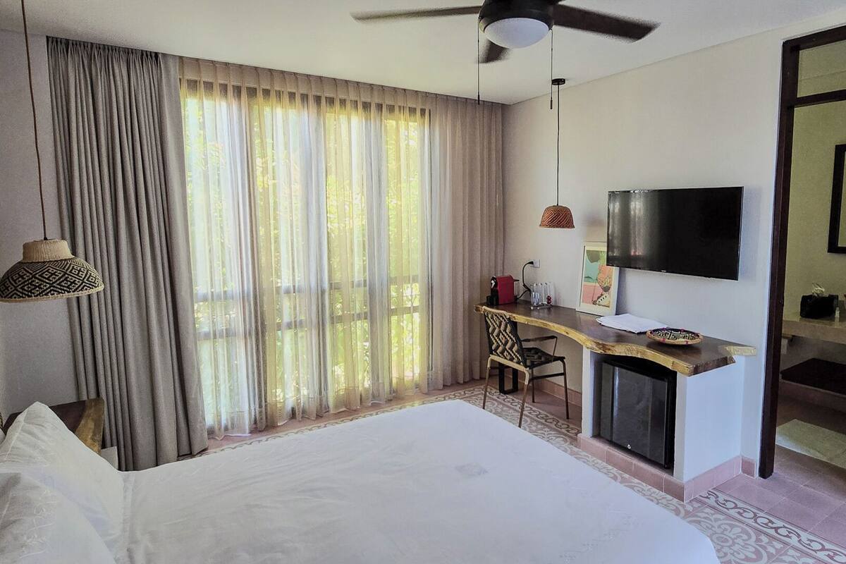 A hotel room with a bed, a desk, a TV, and a bathroom.