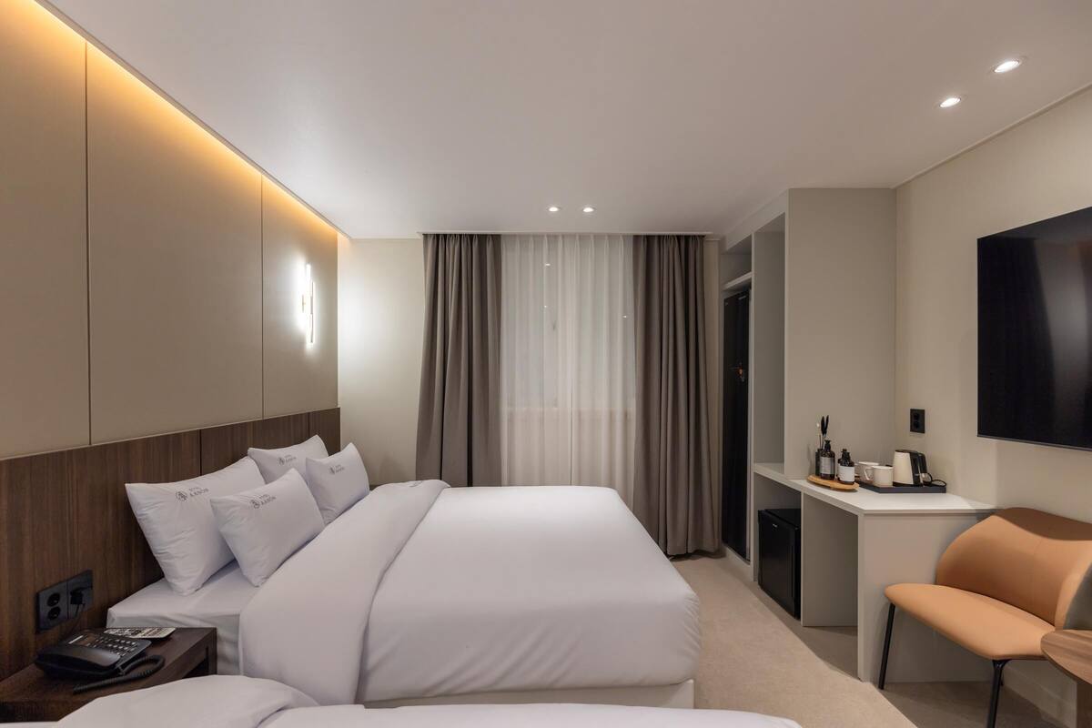 Una habitación de hotel moderna con una cama grande, una mesita de noche y un escritorio con silla.