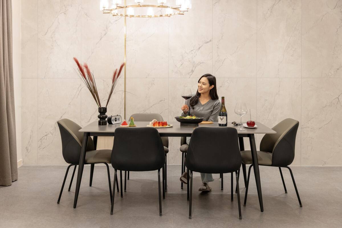 Un comedor con pared de mármol, una araña y una mesa para dos personas con sillas.