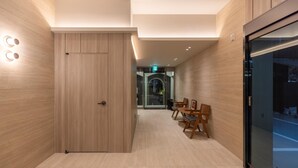Un moderno vestíbulo de hotel con paneles de madera, un mostrador de recepción y un ascensor de vidrio.
