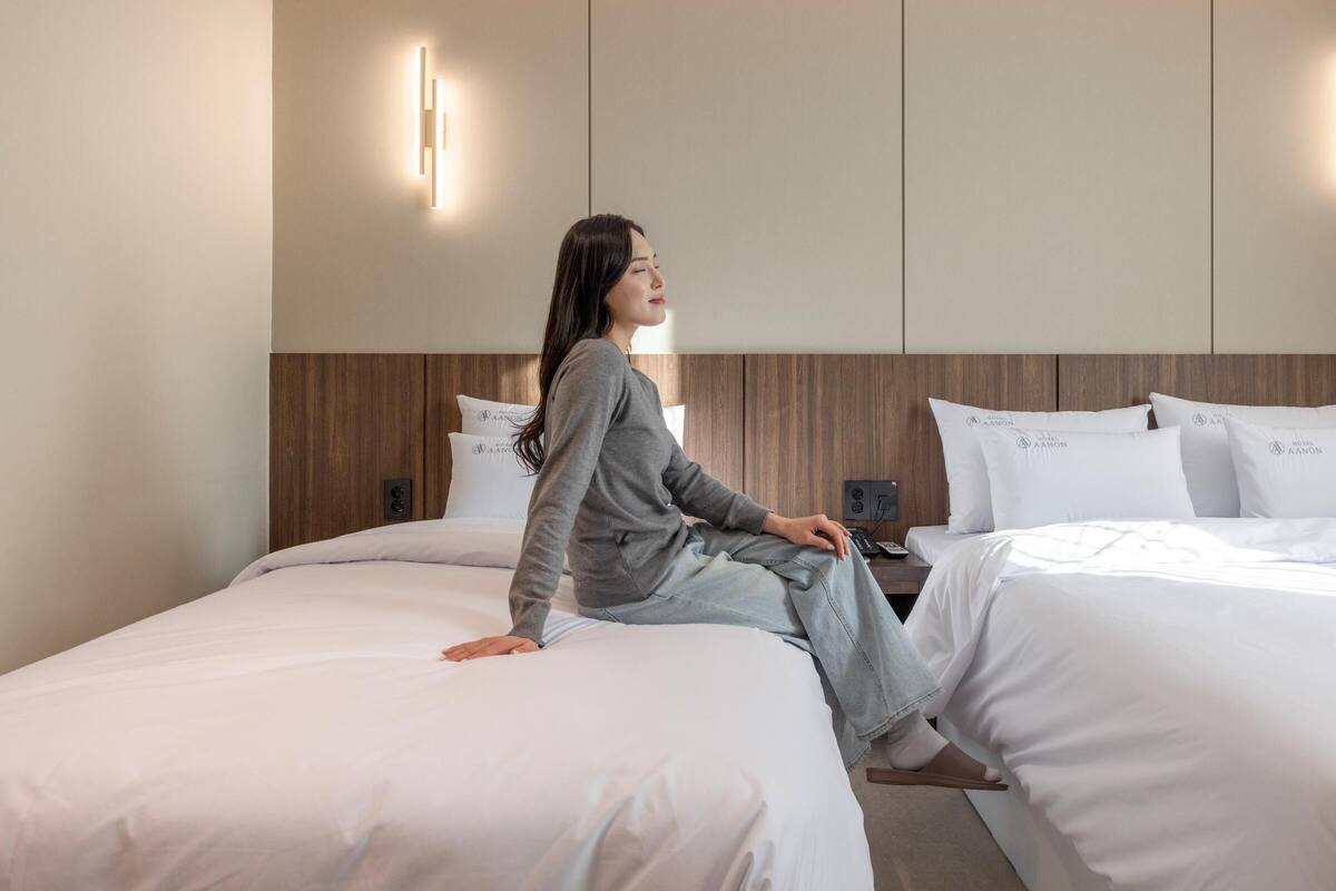 Una habitación de hotel con una cama, una mesita de noche y una lámpara fijada a la pared.