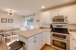A kitchen with white cabinets, a double oven, a microwave, and a dining area with a table and chairs.