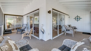 Una habitación amplia con muebles de mimbre, un separador de vidrio y un adorno en la pared.