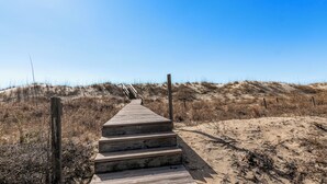 A wooden staircase leading up a sandy beach with a clear sky above. - Discover your dream beach house with an amazing ocean view and lots of deck space on South Beach! (Bald Head Island)