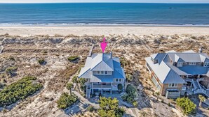 A beachfront property with two houses, a sandy beach, and the ocean. - Discover your dream beach house with an amazing ocean view and lots of deck space on South Beach! (Bald Head Island)