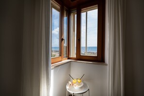 Une chambre d’angle avec vue sur la mer, une petite table avec des boissons et une fenêtre avec des rideaux.