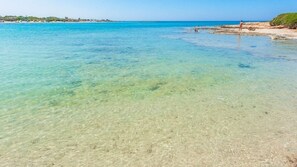 Une plage à l’eau turquoise et limpide, bordée d’un rivage sablonneux.