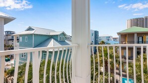 A balcony with white railings overlooking a pool area, surrounded by buildings with various architectural styles.